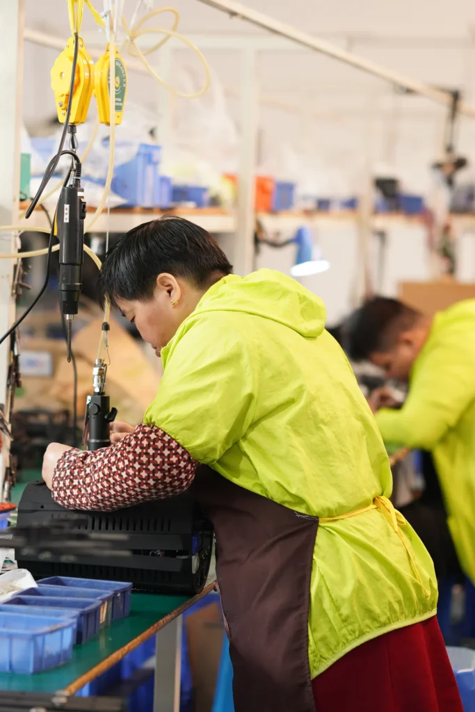 People in production line using screw driver wearing green